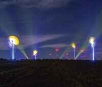 Kunst: Leuchten an Windenergieanlagen zeichnen bunte Bilder in den Nachhimmel.