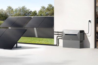 Zu sehen sind Photovoltaik Module, die an einer Garage angebracht bzw. auf einer Terasse stehen und die mit einem Anker Solix Speicher verbunden sind.