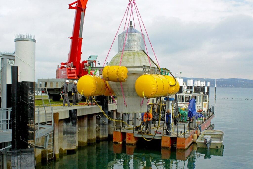 graue Betonkugel an rotem Kran - der Test für den Unterwasser-Pumpspeicher am Bodensee. 