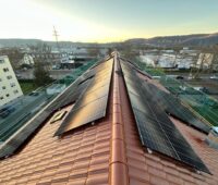 Solarmodule auf einem Mehrfamilienhaus mit Satteldach im urbanen Umfeld.