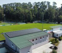 Vereinsheim an einem Fußballfeld mit PV-Anlage auf dem Dach.