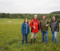 Vier Personen fröhlich auf einer Wiese mit Windkraftmodellen in der Hand.