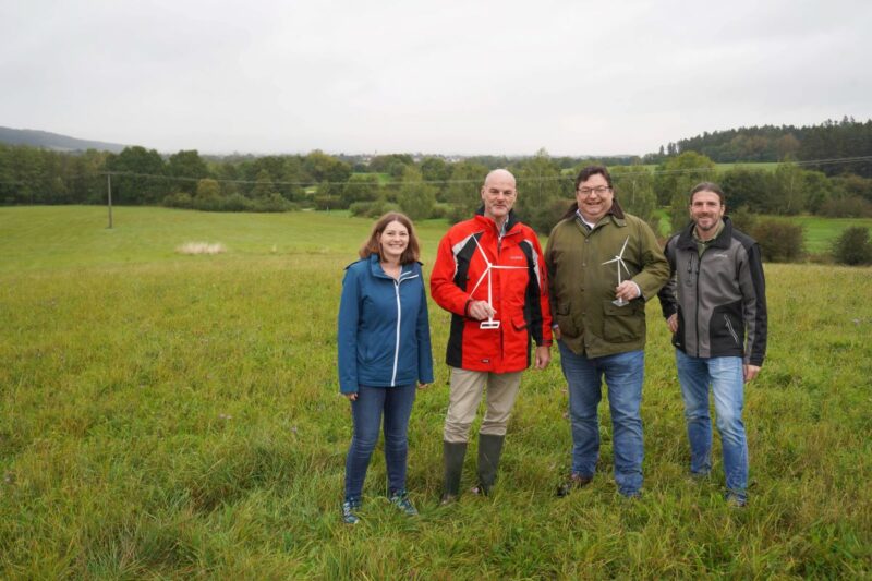 Vier Personen fröhlich auf einer Wiese mit Windkraftmodellen in der Hand.