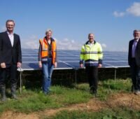 4 Personen vor einem Solarkraftwerk bei blauem Himmel.