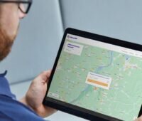 Mann schaut auf Tablet, das Landkarte zeigt - automatische Suche nach Netzanschluspunkt für Photovoltaik-Anlagen