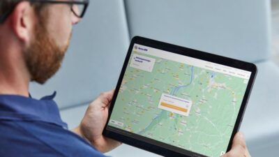 Mann schaut auf Tablet, das Landkarte zeigt - automatische Suche nach Netzanschluspunkt für Photovoltaik-Anlagen