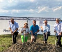 5 Personen vor einem Aufsteller zu Agri-PV beim Spatenstich auf dem Land.