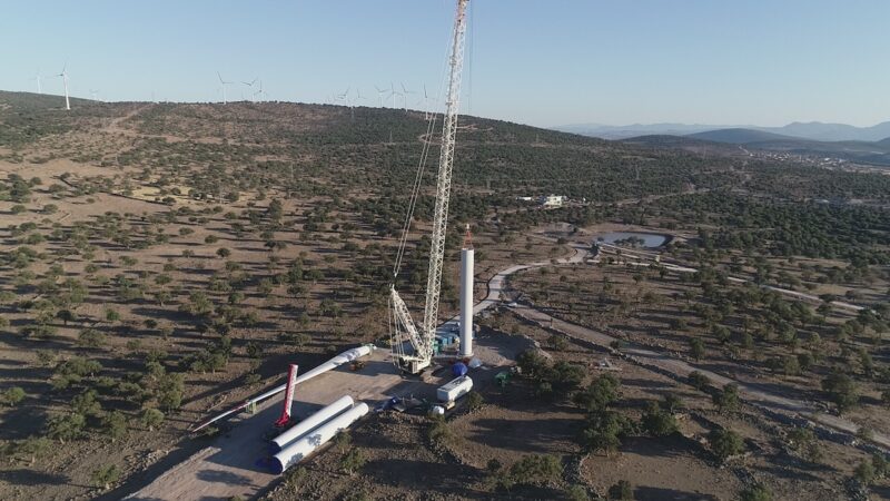 Karge Landschaft, Windenergie-Anlagen im Hintergrund, vorne eine Anlage im Aufbau - Nordex-Auftrag aus Spanien.