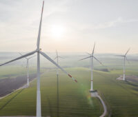 Mehrere Windkraftanlagen von Hersteller Nordex auf grünen Wiesen. Ein Abbild des europäischen Windmarkts.