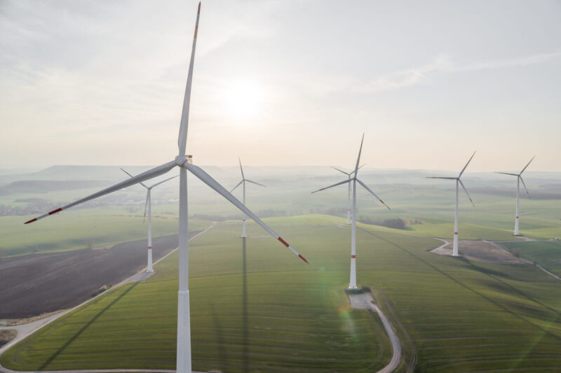 Mehrere Windkraftanlagen von Hersteller Nordex auf grünen Wiesen. Ein Abbild des europäischen Windmarkts.