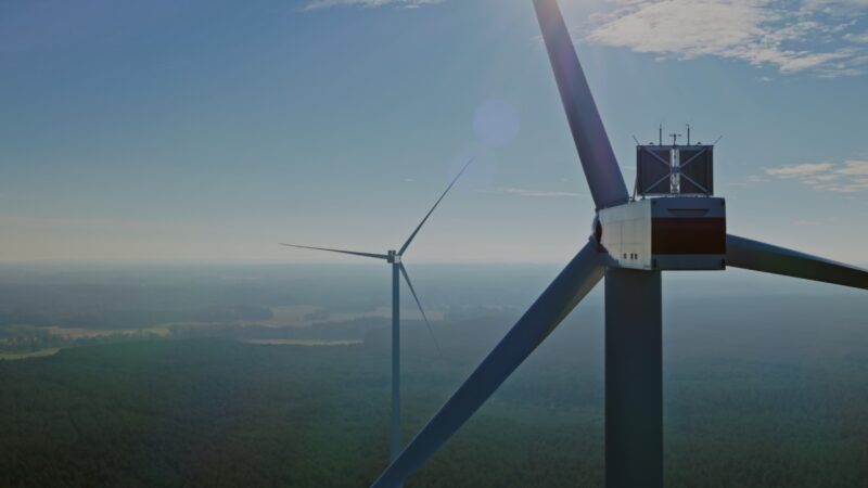 Gondel einer Windkraftanlage in. luftiger Höhe mit Blick auf Flachland in der Tiefe.