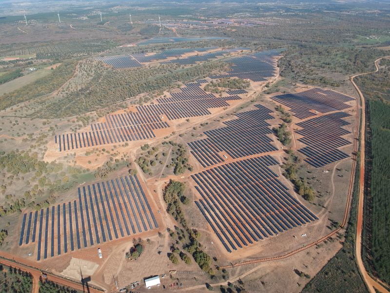 Luftaufnahme eines PV-Parks in Spanien mit Windenergie im Hintergrund