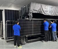 Mehrere Personen bewegen große Solarmodule in einer Halle.