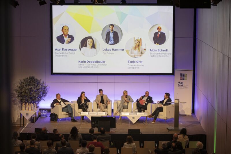 Podiumsdiskussion auf Pv-Konferenz in Österreich: 6 Menschen auf breiten Sesseln, Projektion mit Namen und Parteien