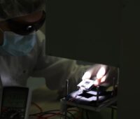 Ein Mensch legt eine Perowskit-Tandem-Solarzelle in einen Sonnensimulator, um den Wirkungsgrad zu vermessen.