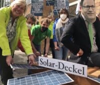 Protestierende mit symbolischen Photovoltaik-Modulen in einer Kiste mit Deckel
