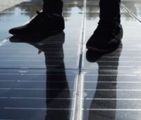 Eine solare Gehwegplatte mit einem paar beschuhter Füße.
