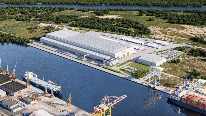 Blick von oben auf eine Fabrikhalle an einem Kanal - die neue Fabrik für Offshore-Windenergie-Türme von Windar in Stettin.