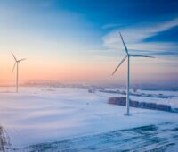 Windturbinen in einer flachen Winterlandschaft bei Sonnenuntergang.