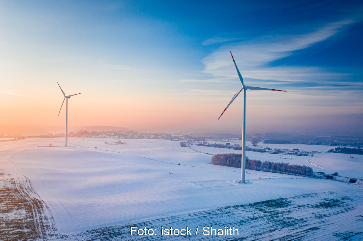 Windturbinen in einer flachen Winterlandschaft bei Sonnenuntergang.