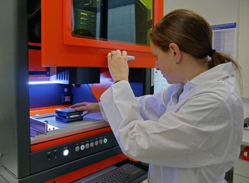 Eine Wissenschaftlerin im weißen Kittel arbeitet im Labor.
