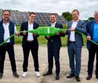 Eröffnung einer Photovoltaik-Anlage in Mecklenburg-Vorpommern: fünf Männer halten einen großen grünen Stecker.