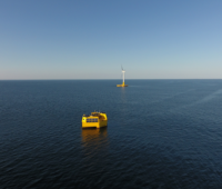 Blick übers Meer, ein gelbes Boot und ein Offshore-Windrad