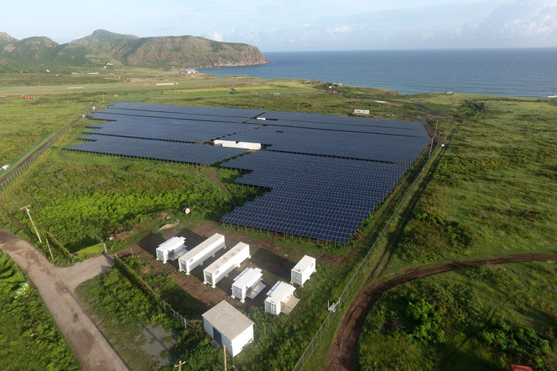 Luftaufnahe Solarpark mit Technik-Containern - Hintergrund: Karibische See