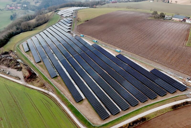 Luftbild zeigt PV-Freifläche von Wiesen und Äckern umgeben.