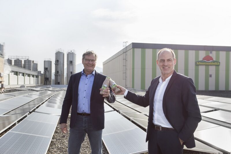 Zu sehen die Geschäftsführer Klaus Preiser von Badenova Wärmeplus und Andreas Schneider von Schwarzwaldmilch die sich zur Fertigstellung der Photovoltaik-Anlage auf dem Dach mit einem Milchprodukt zuprosten.