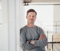 Portraitfoto von Jochen Schwill, lässig an einer Wand lehnend