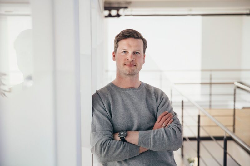 Portraitfoto von Jochen Schwill, lässig an einer Wand lehnend