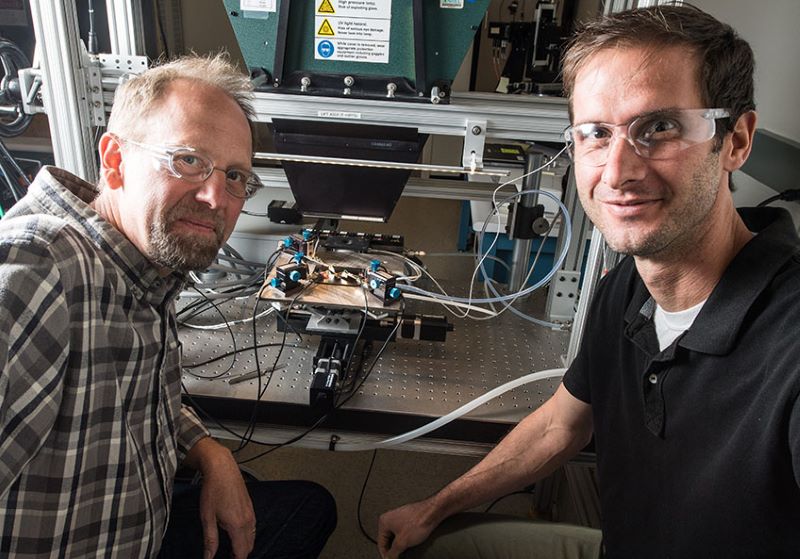 Zwei Forscher sitzen an ihrem labortisch vor einer elektrischen Apparatur.