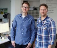 Die beiden Geschäftsführer von Polarstern Simon Stadler und Florian Henle stehend in Büroumgebung.