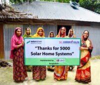 Frauen aus Bangladesch vor Haus mit Solarhome-System.