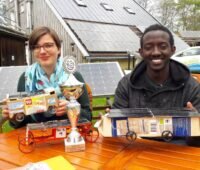 Ein Mädchen und ein Junge präsentieren ihre selbstgebastelten Solarfahrzeuge