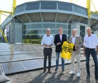 Vier Personen auf dem Stadiondach des BVB neben existierender PV-Anlage.