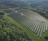 Luftbild eines Solarkomplexes umgeben von Wald.