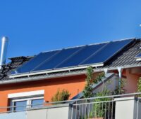 Foto einer Solarthermie-Anlage auf einem Wohnhaus vor blauem Himmel.