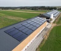 langes, flaches Gebäude mit Solarthermie-Kollektoren auf dem Dach - ein Hühnermast-Betrieb