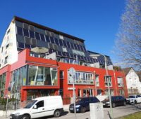 Zu sehen ist ein Wohn- und Geschäftshaus in München, dessen Solarthermie-Anlage von der BEG-Förderung profitieren könnte, wenn sie dieses Jahr errichtet würde.