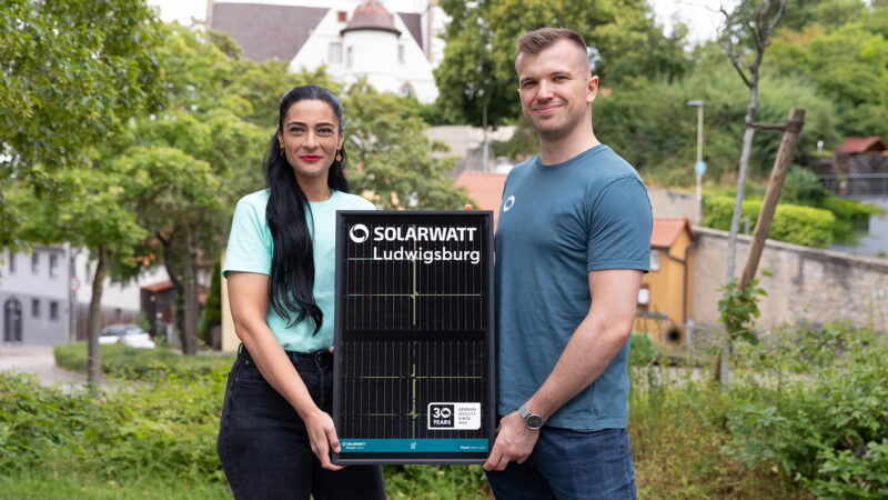 Eine Frau und ein Mann halten ein kleines Solarmodul mit dem Schriftzug Solarwatt Ludwigsburg.
