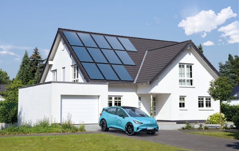 Das Bild zeigt ein großes Einfamilienhaus mit Photovoltaik-Anlage auf dem Dach und einem Elekotrauto vor dem Haus.