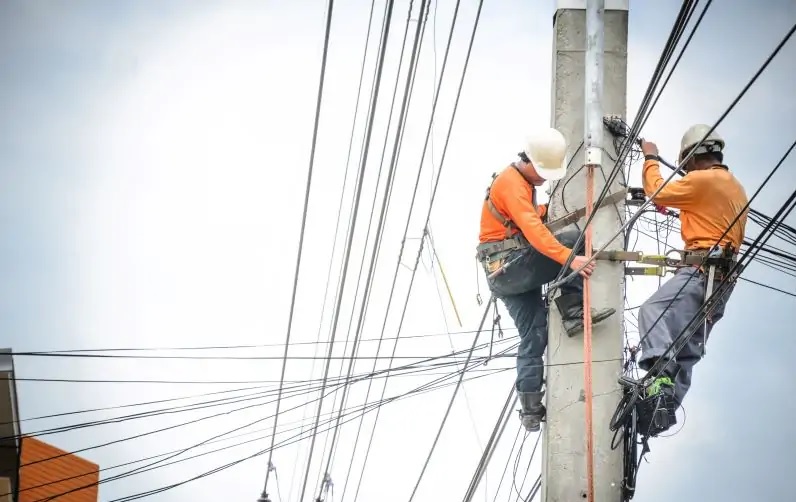 Zwei Männer auf einen Strommast als Symbol für den Stromnetzengpass in Oranienburg.