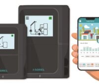 Die Solarthermie-Regler TDC Smart von Sorel mit Hand und App auf dem Handy.