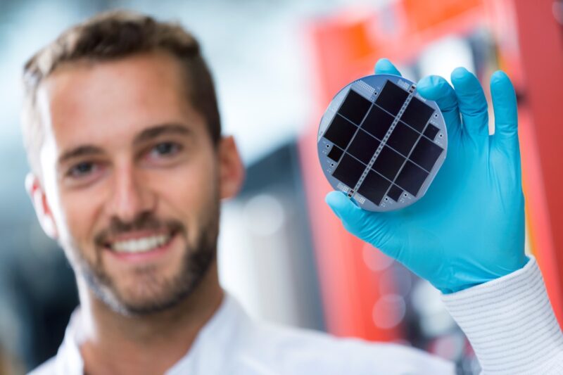 Der Wissenschaftler Markus Feifel präsentiert erfreut eine Tandem-Solarzelle.