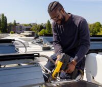 Im Bild ein Installateur, der eine PVT-Anlage von Triple Solar auf dem Dach montiert.