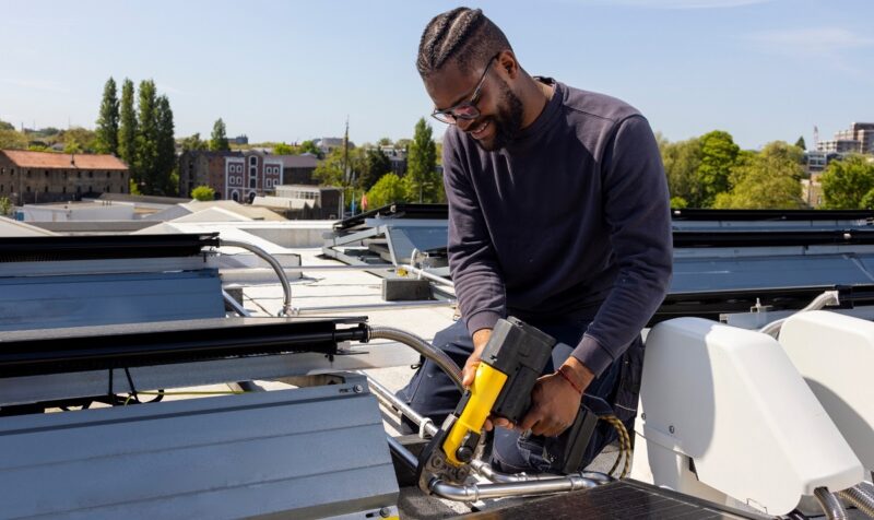 Im Bild ein Installateur, der eine PVT-Anlage von Triple Solar auf dem Dach montiert.
