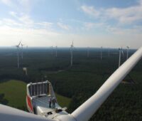 Ein Windpark in Deutschland von oben. Auf einer der Gomdeln stehen zwei Menschen
