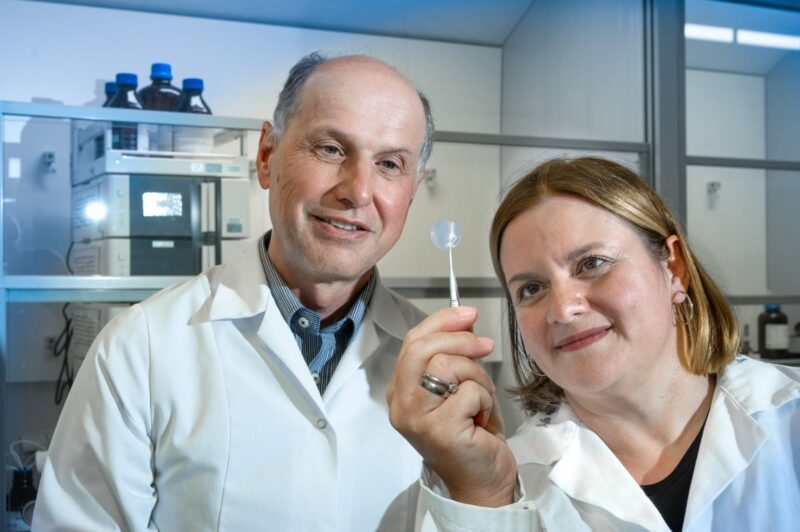 Eine Wissenschaftlerin udn ein Wissenschaftler betrachten ein kreisrundes Polymer.